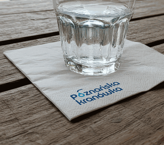 Szklanka wody na serwetce z logo Poznańska Kranówka